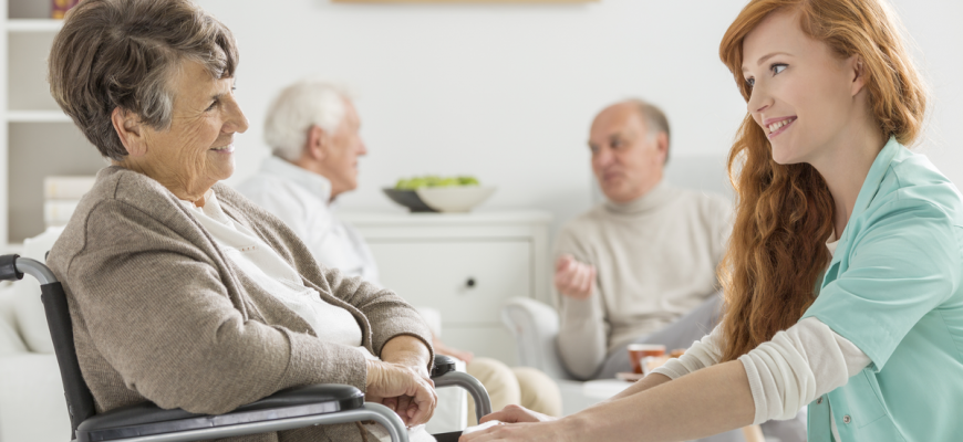 An elderly woman and a staff member at an assisted living home.