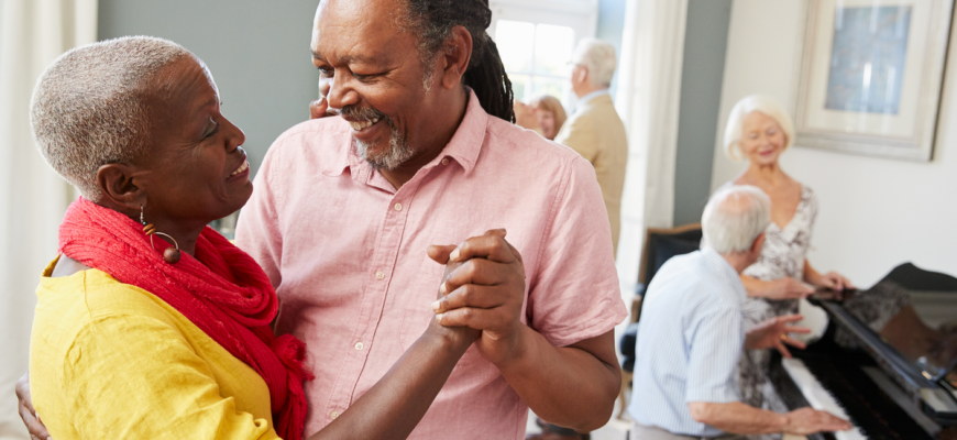 older couple dancing in foreground, another couple playing piano in background