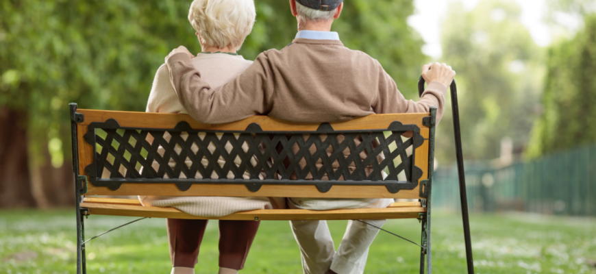 Elder couple sitting on bench of assisted living facility