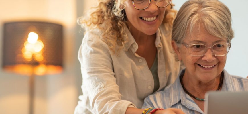 Older woman looking at computer with younger woman smiling and looking over her shoulder