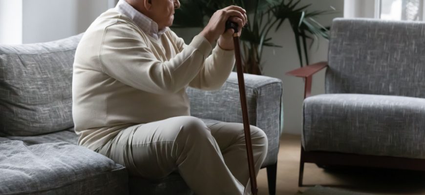 Man sitting on the couch with a cane