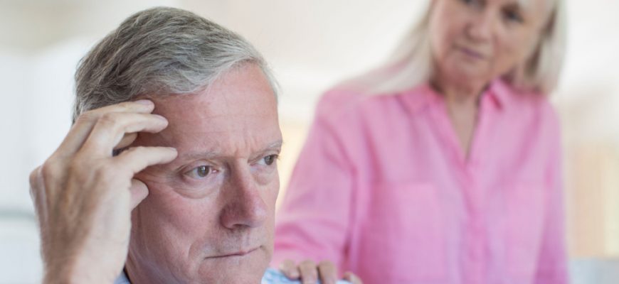 Elderly man putting his hand on his head having a hard time remembering